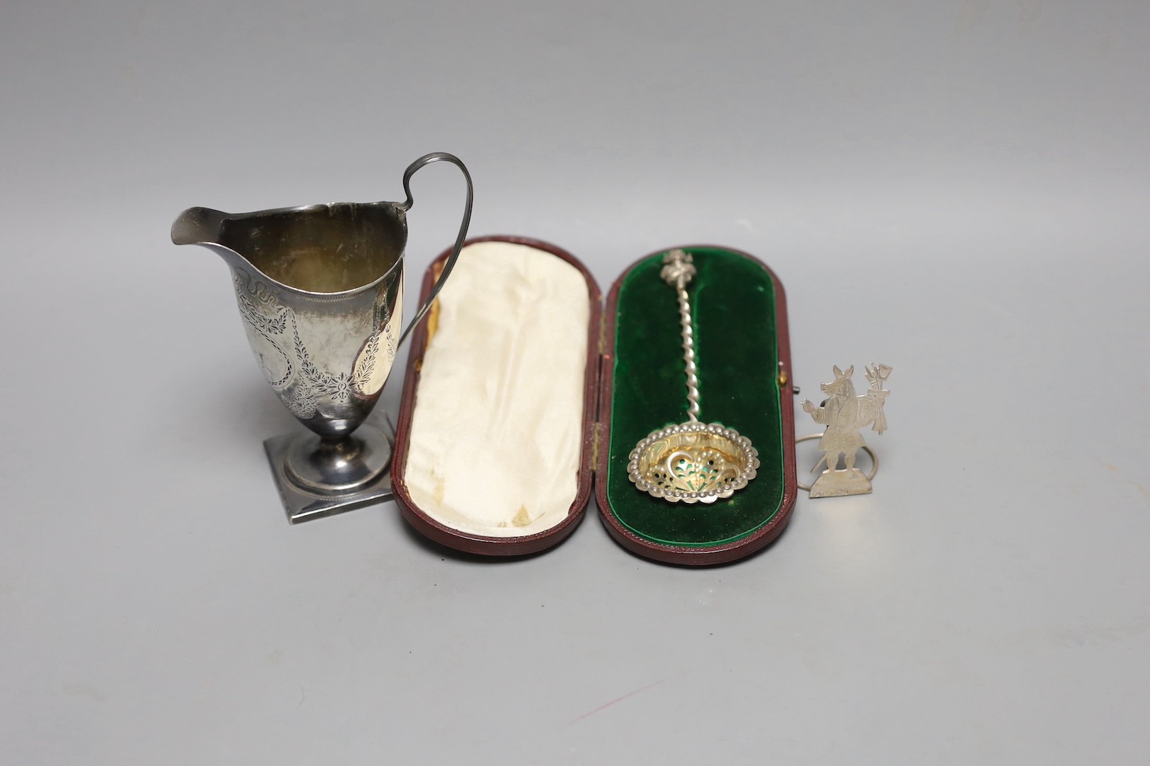 A George III silver helmet shaped cream jug, London, 1791, 13.2cm(a.f.), a silver menu holder and a cased silver sifter spoon.